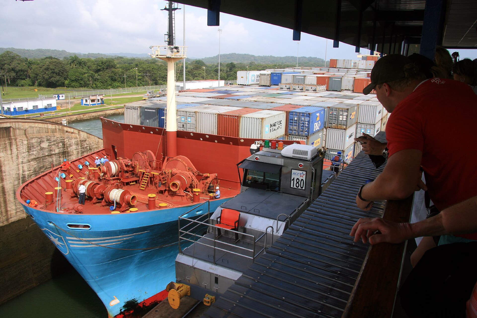 Container ship transiting the Panama Canal locks with tugboat assistance
