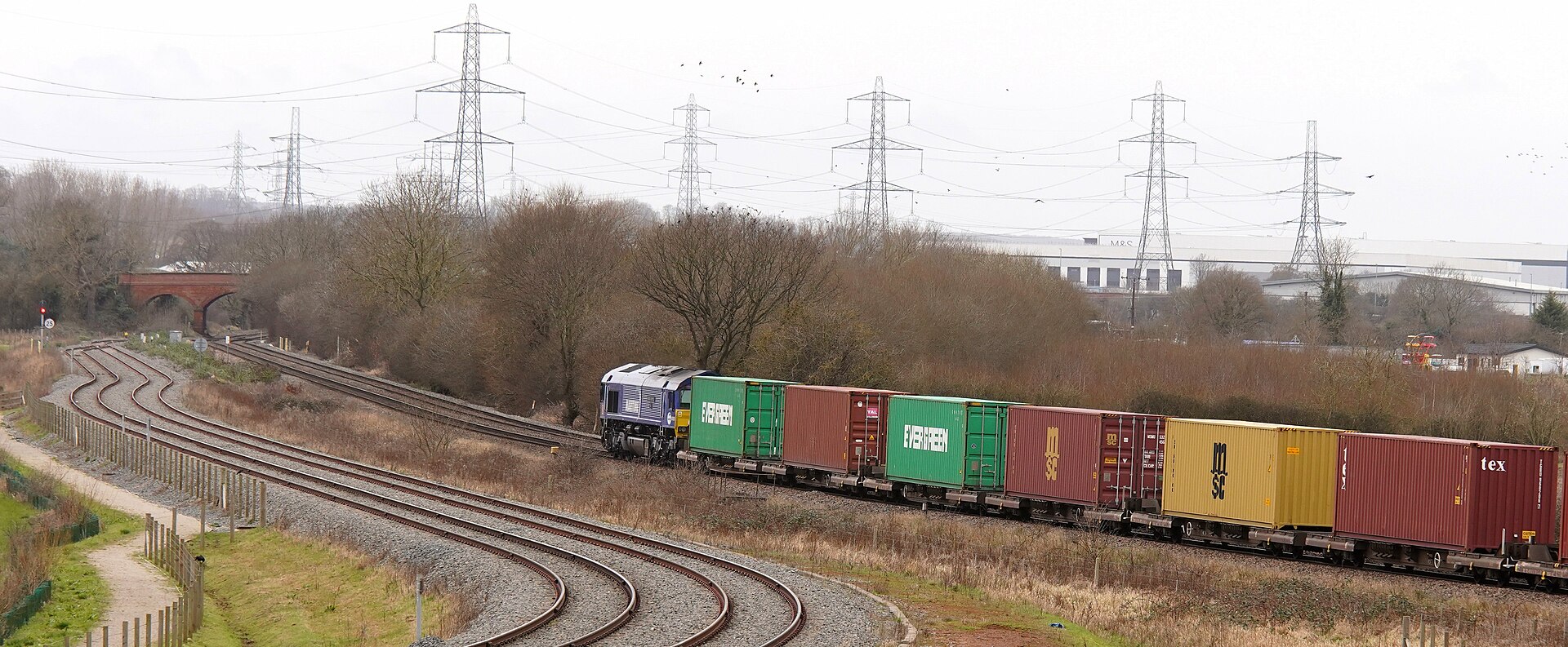 Norfolk Southern intermodal train passing through rail yard in winter conditions