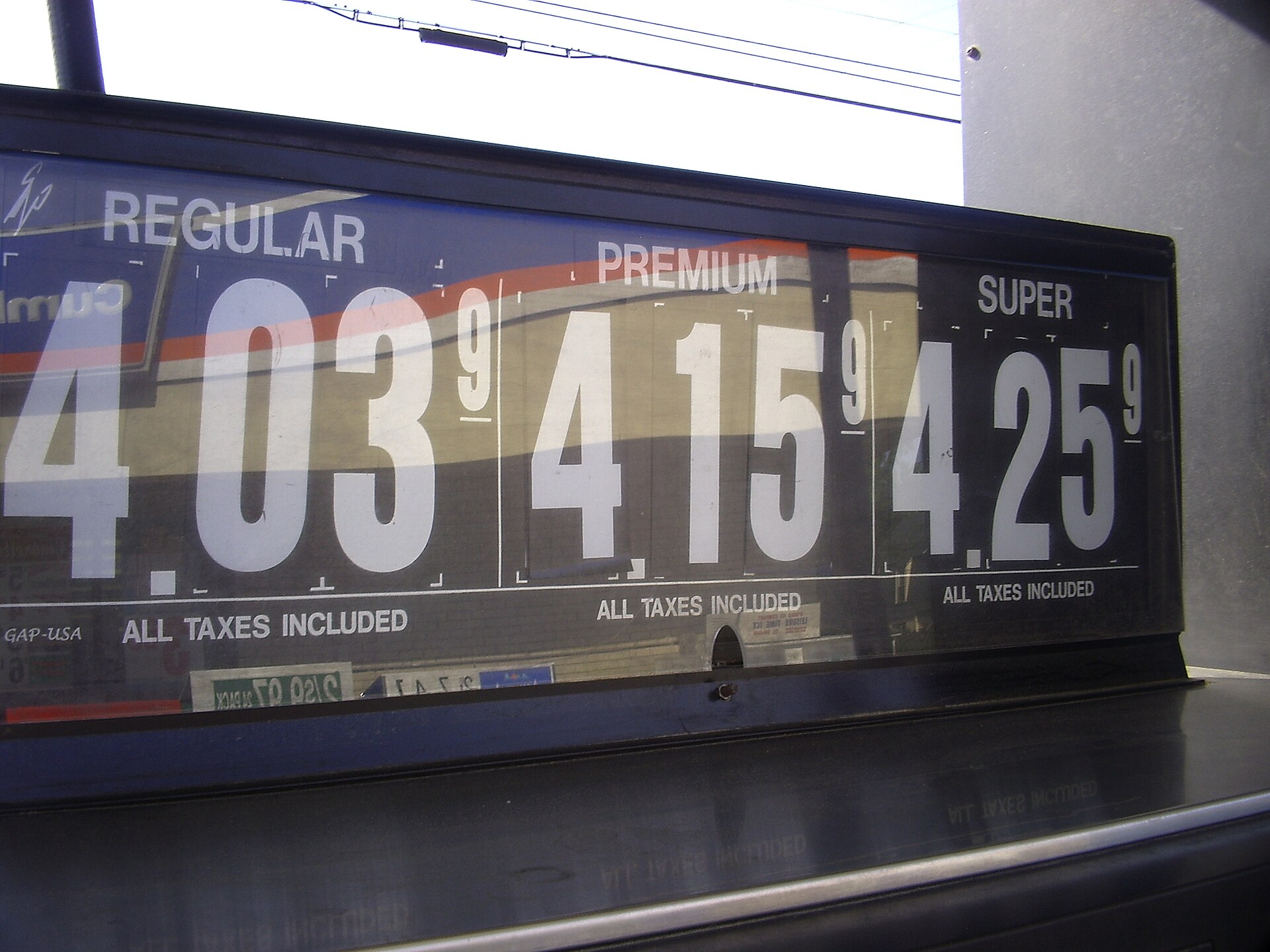 Oil barrels stacked at a refinery terminal with price chart overlay showing Brent crude decline