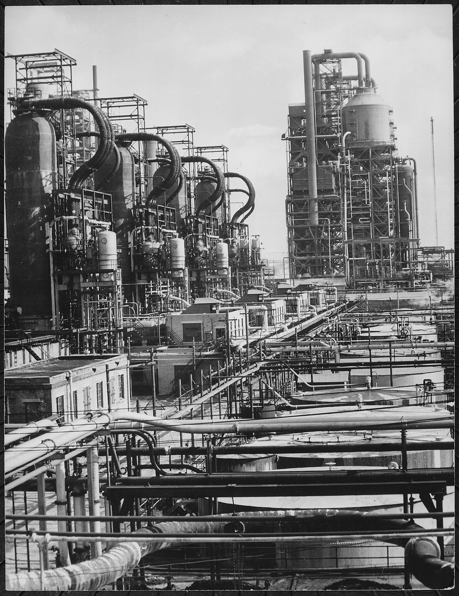 Oil barrels stacked at a refinery terminal with price charts overlaid