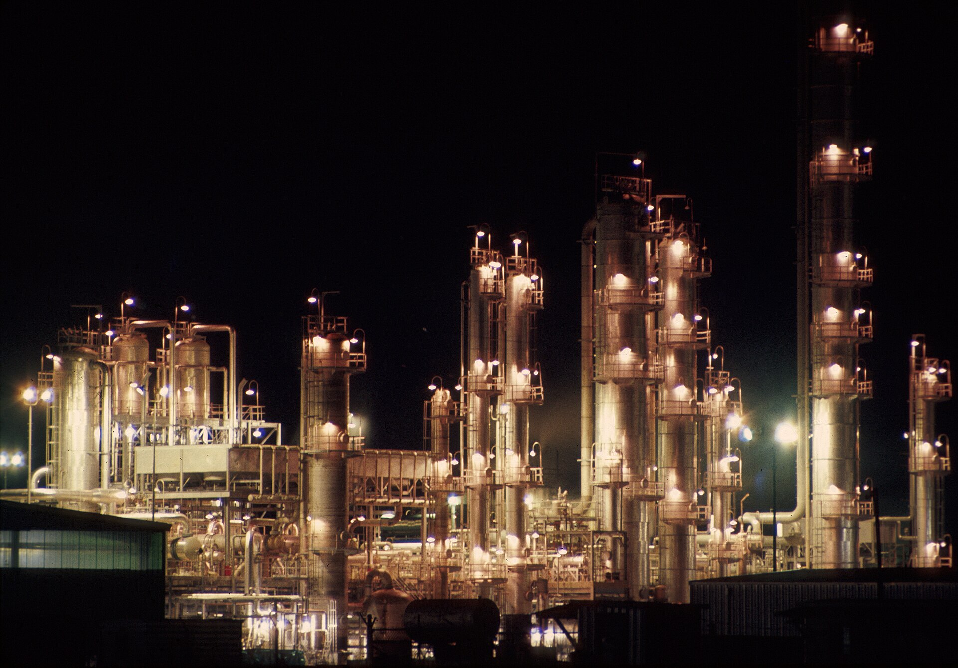 Oil refinery with flames and smoke rising from industrial facility