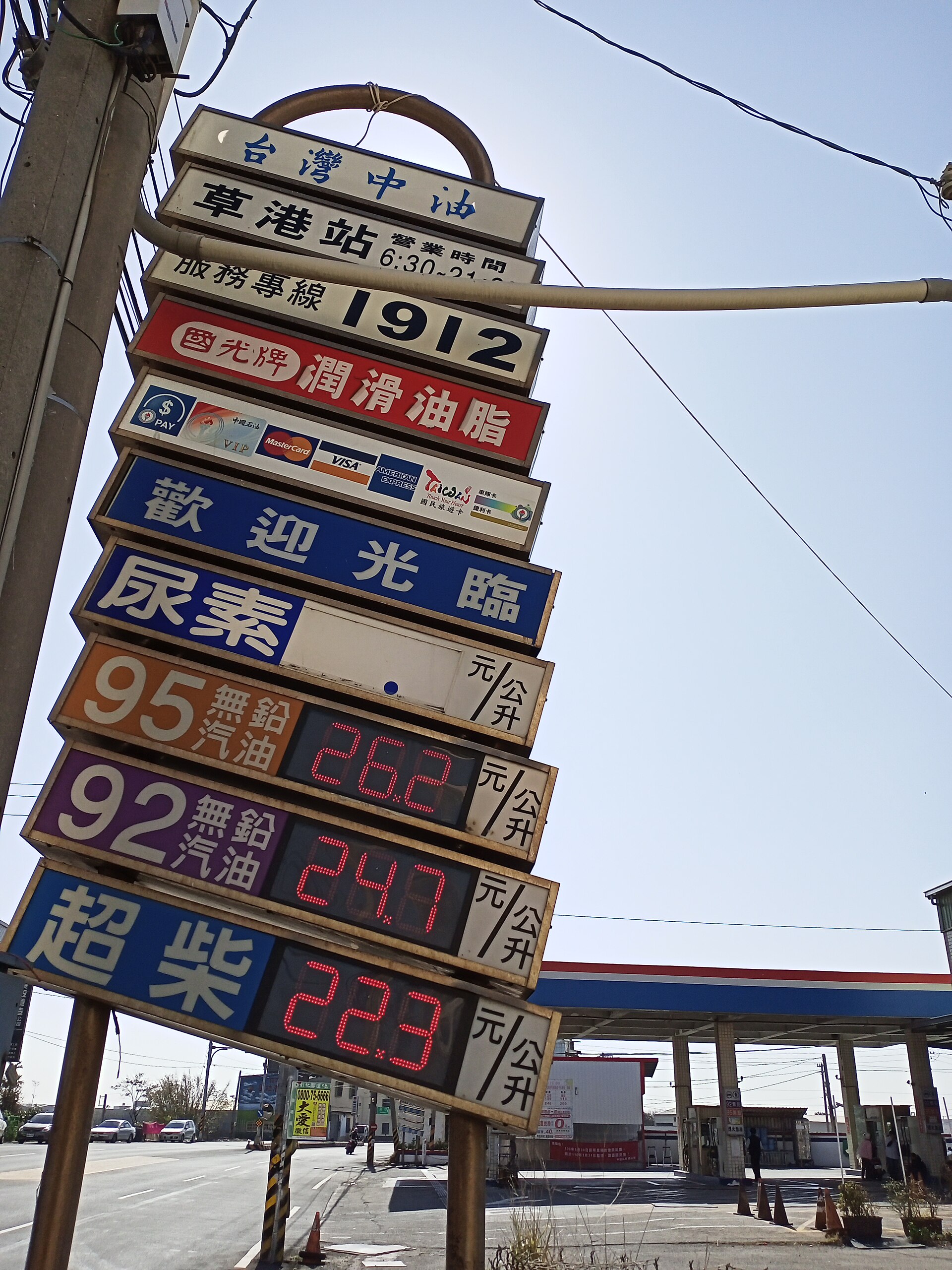 Fuel pump nozzle at truck stop with diesel price display showing recent price decline