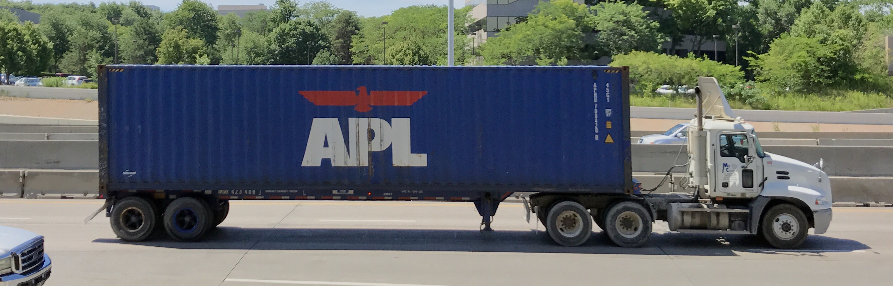 Stacked shipping containers at a U.S. port terminal with cranes in the background