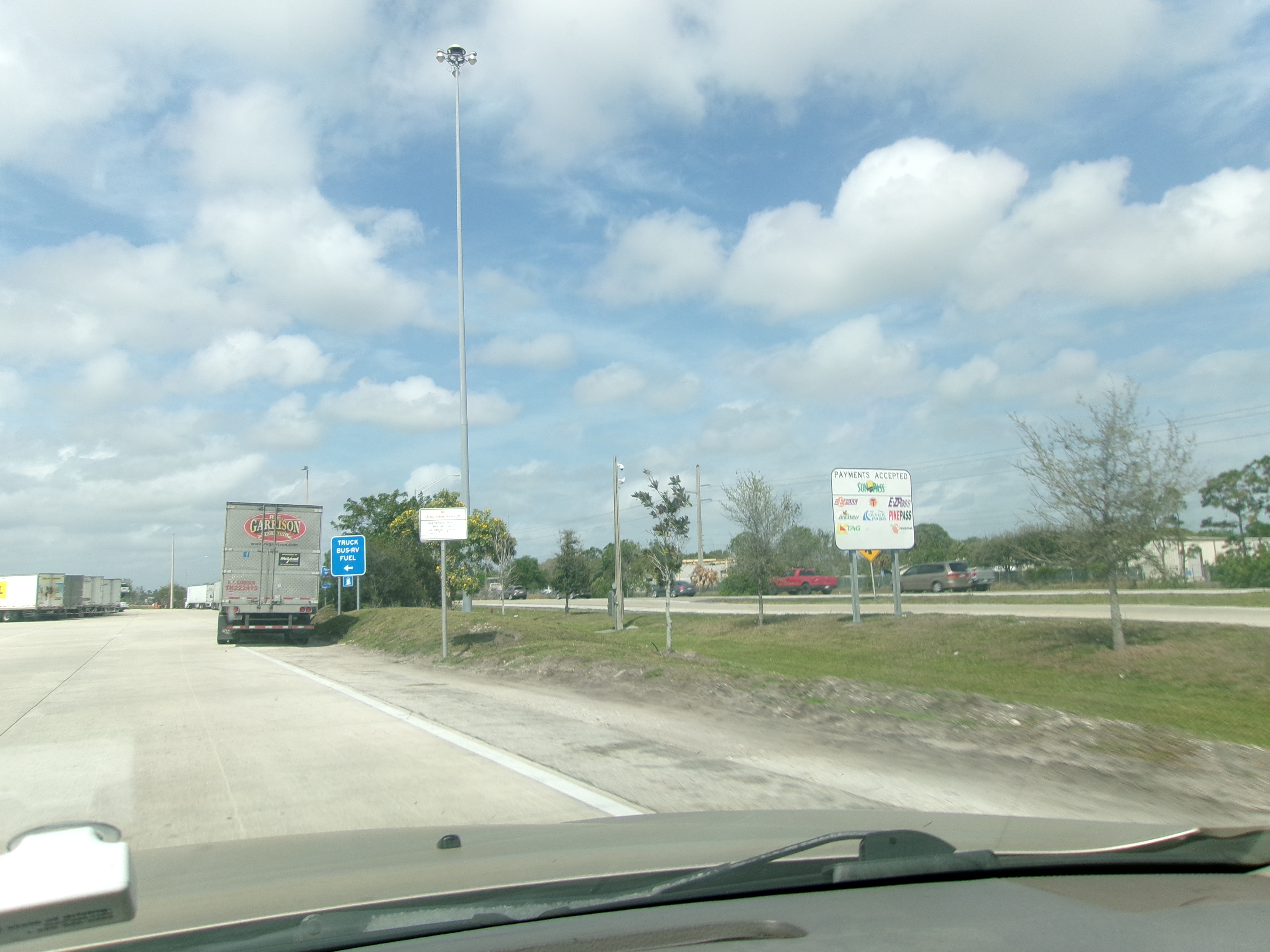 Commercial truck passing through Illinois tollway plaza with I-PASS transponder reader overhead
