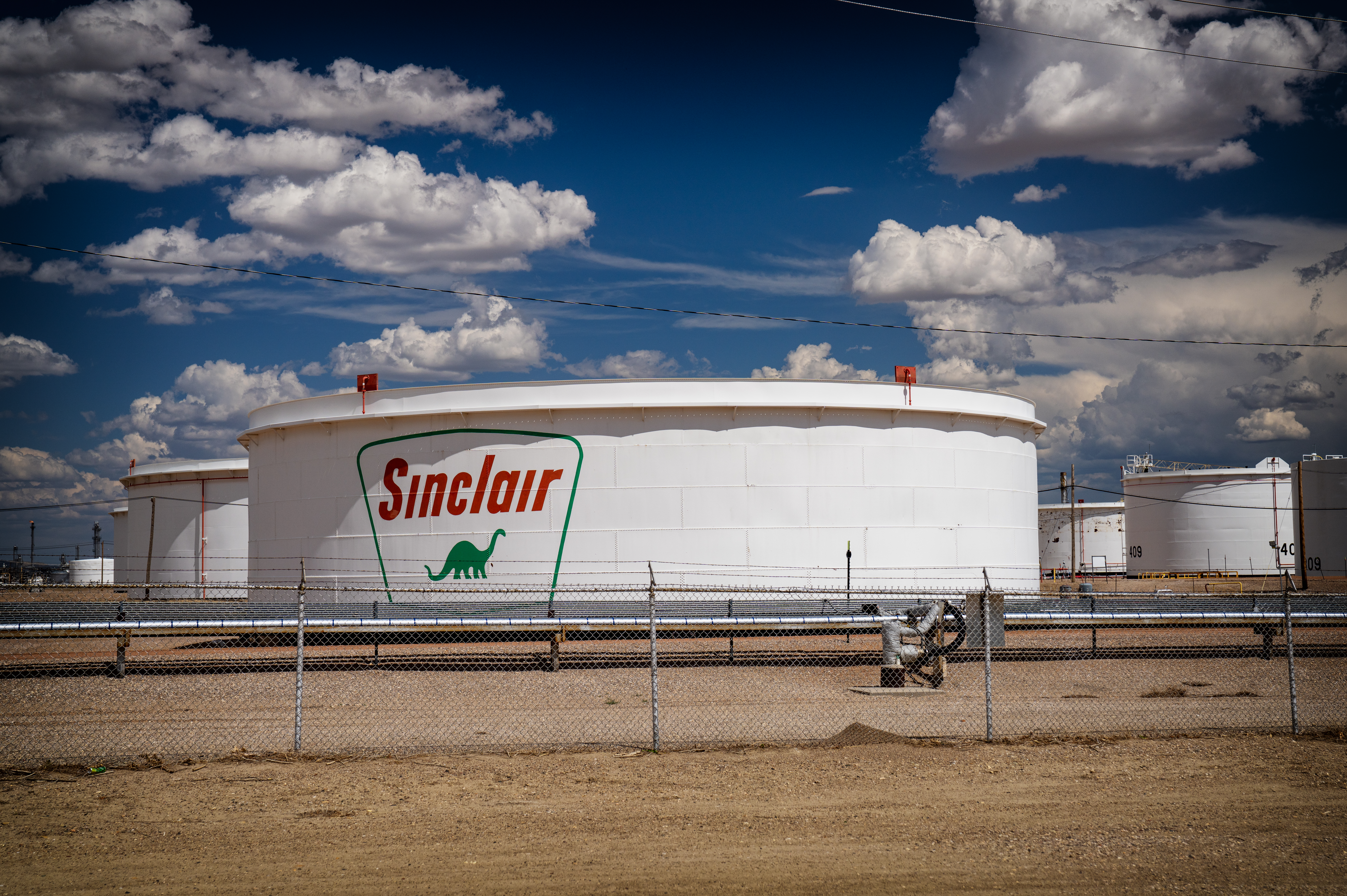 Oil barrels stacked at a refinery terminal with price chart overlay showing Brent crude movement