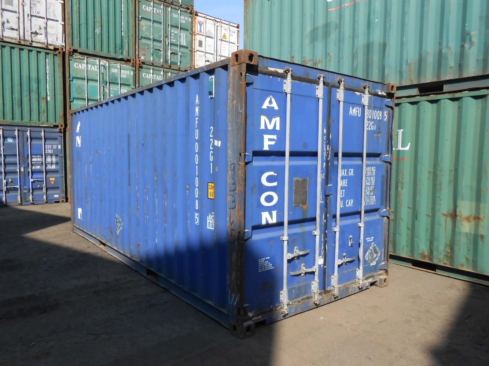 Intermodal container stacks at a rail terminal with trucks in the background