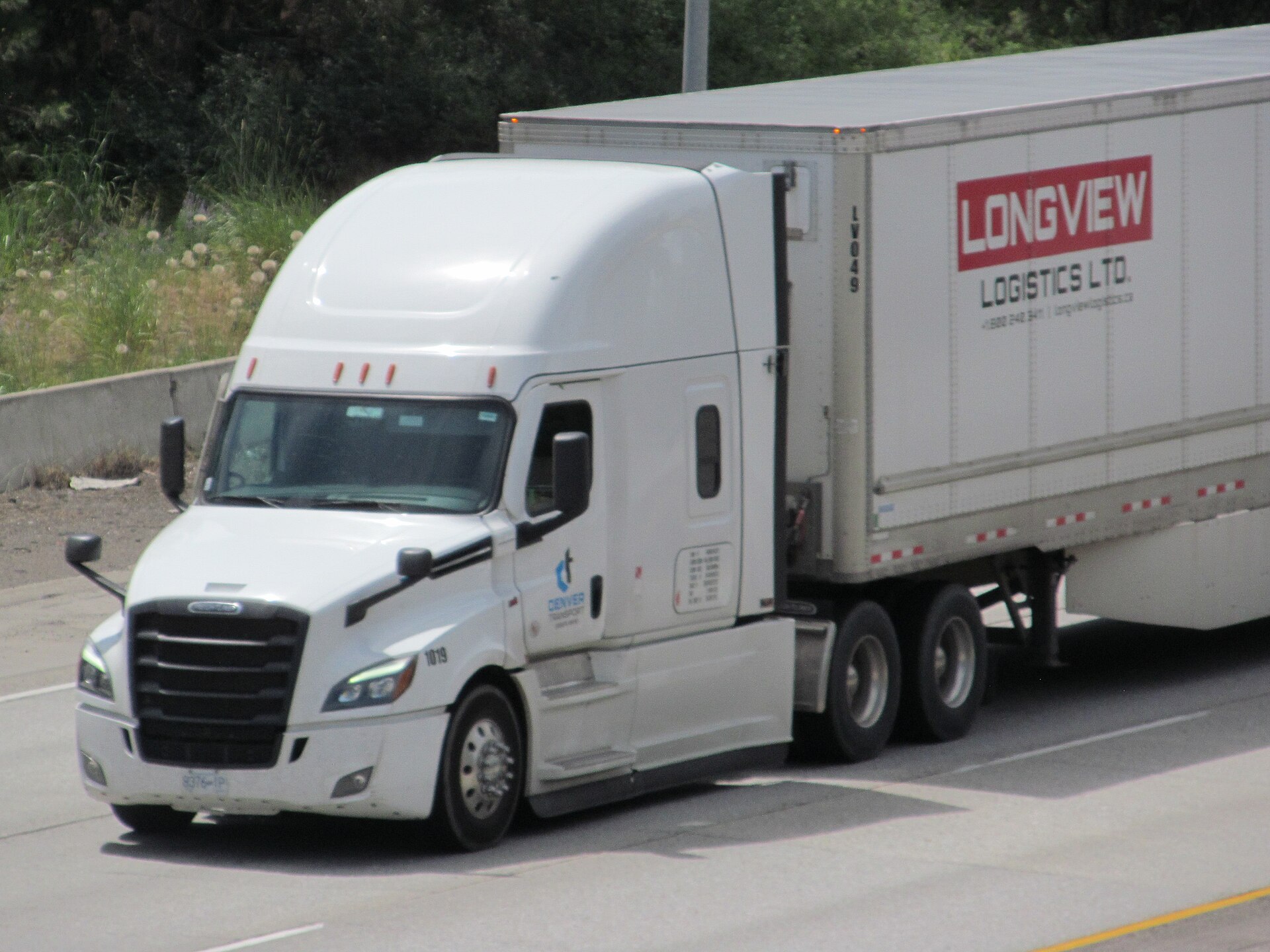 Truck driver reviewing FMCSA registration paperwork on laptop at truck stop