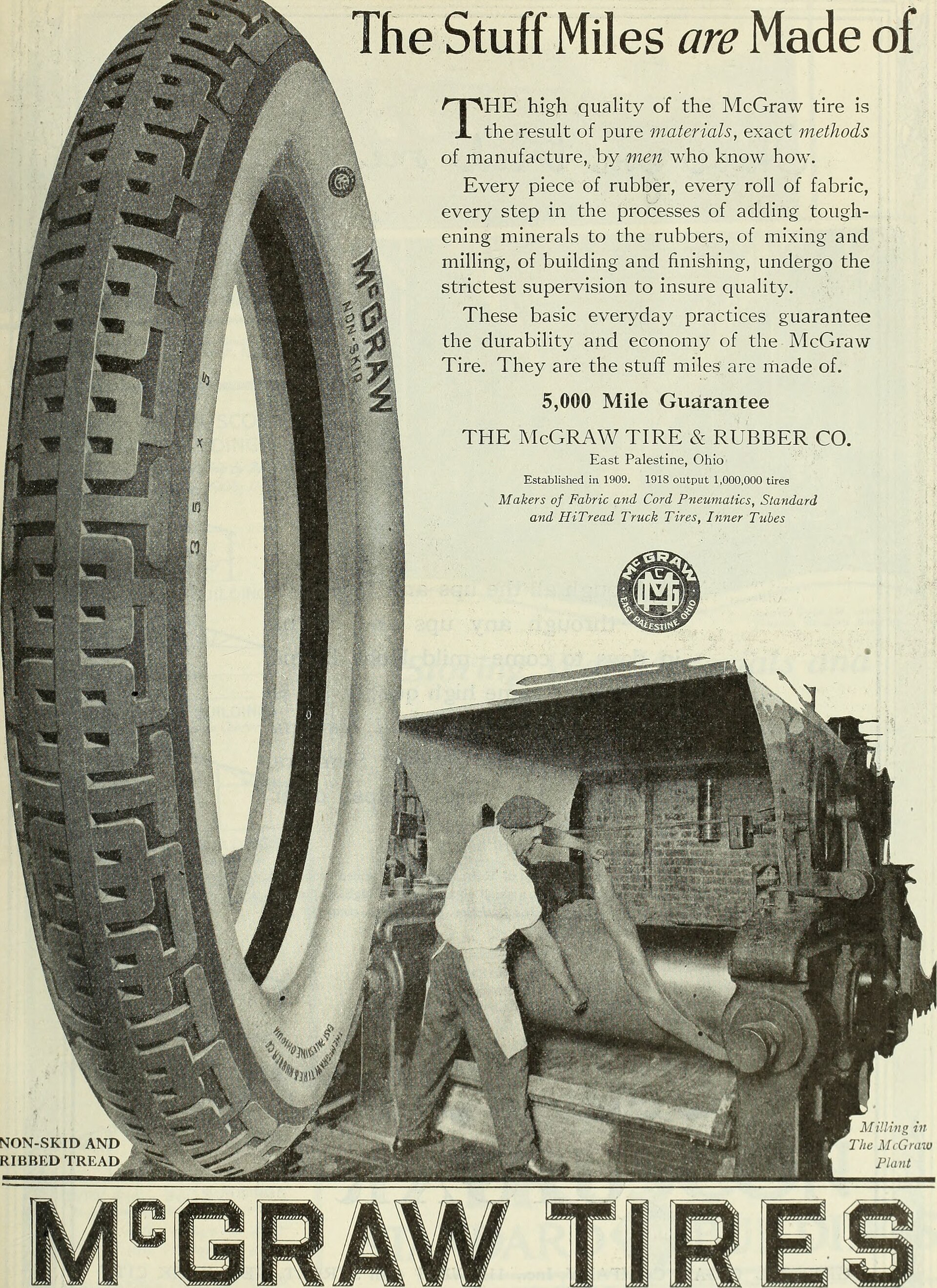 Commercial truck tire in a retread plant with automated buffing and tread application equipment visible in the background