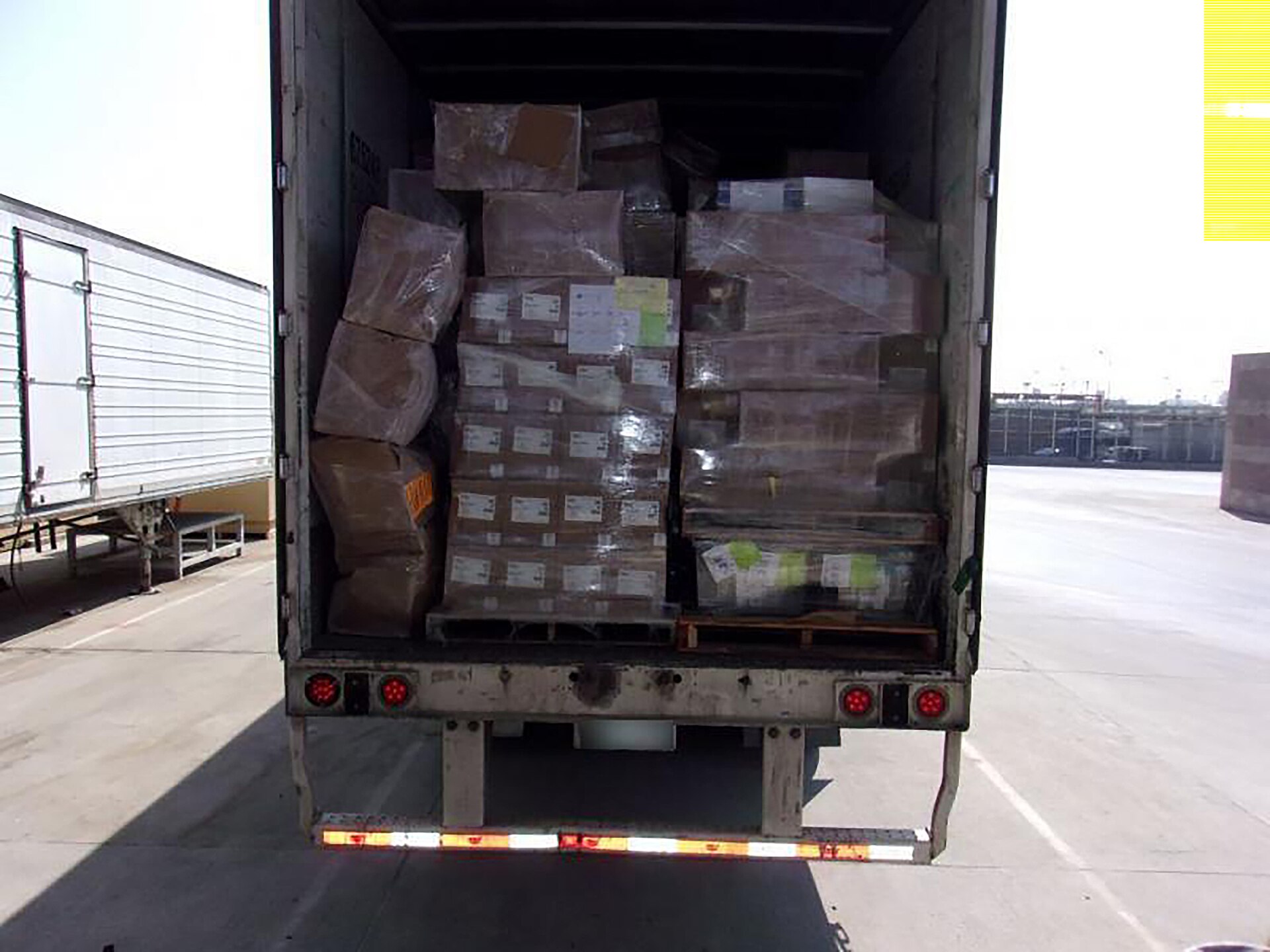 Semi-truck crossing US-Mexico border checkpoint with security inspection lane visible