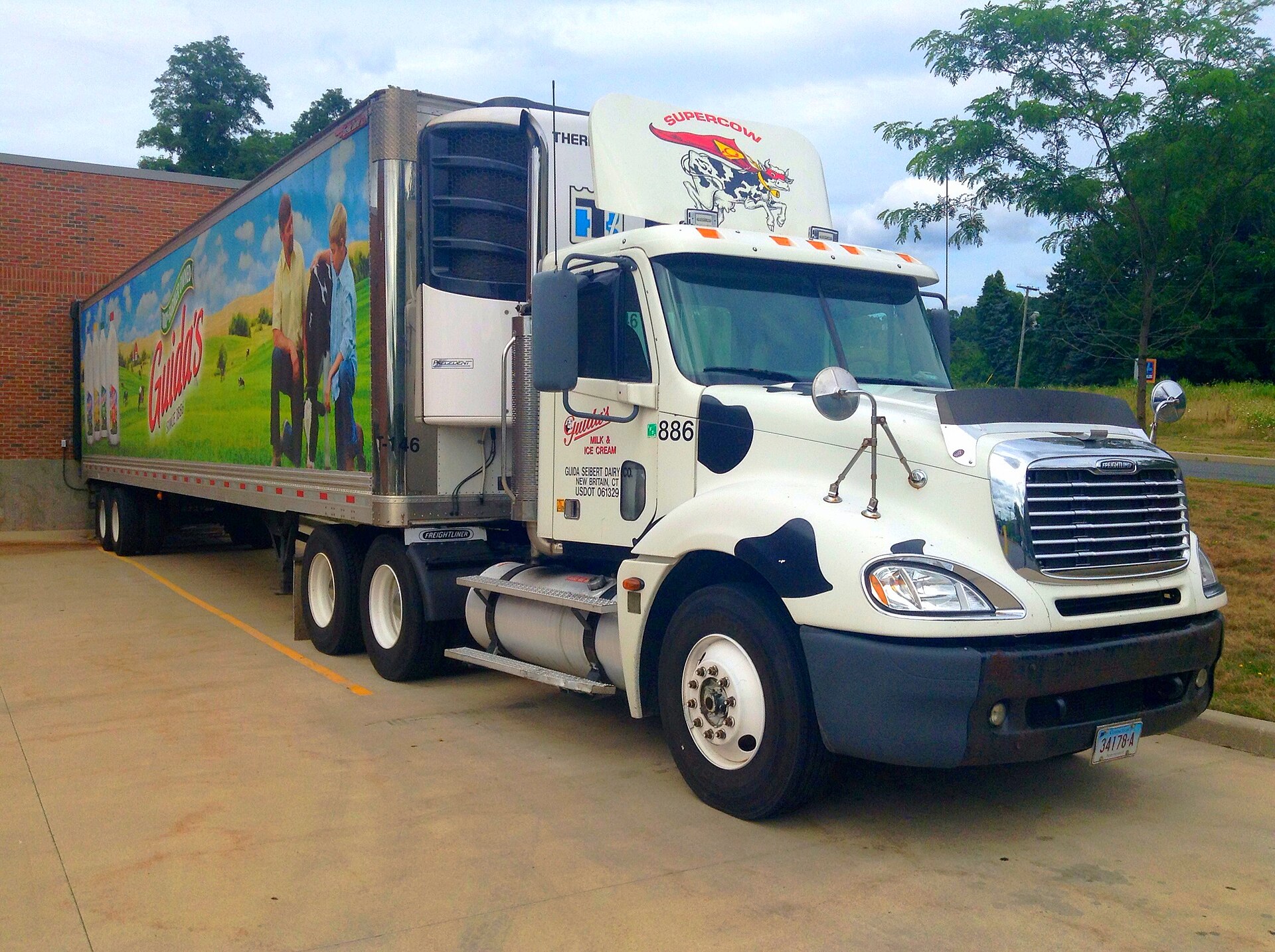 Freight broker reviewing carrier safety documents at desk with computer screen showing FMCSA data