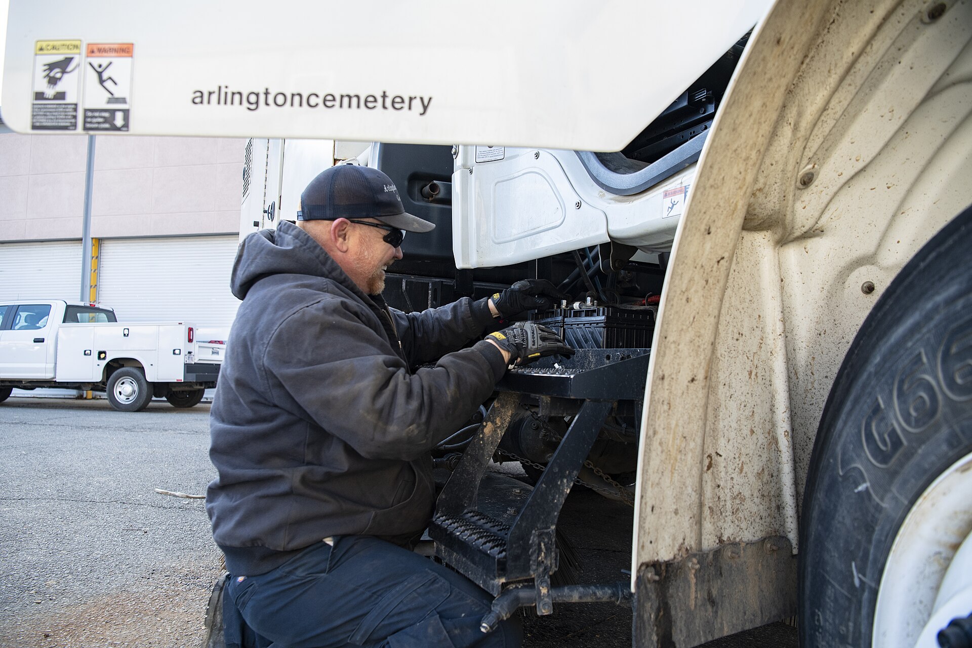 Mobile maintenance technician working on commercial truck in fleet yard with diagnostic equipment and welding tools