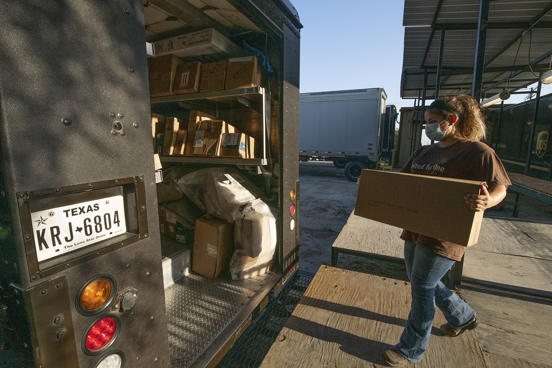 UPS delivery truck parked at loading dock with packages visible in cargo area